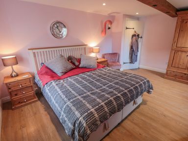A bedroom with a bed lamps bedside tables a chair a wardrobe and a door at Ericas eaven Farndale near Kirkbymoorside