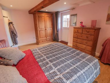 A bedroom with a bed chest of drawers wooden wardrobe and a door at Ericas eaven in Farndale near Kirkbymoorside