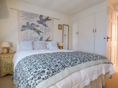 A bedroom with a double bed a decorative blanket bedside tables with lamps a wardrobe and a wall hanging of birds at High House in Newton in Cartmel near Cartmel