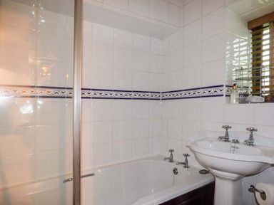 A bathroom with a bathtub a pedestal sink and window blinds at High House in Newton in Cartmel near Cartmel