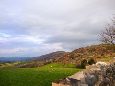 A rural landscape with green fields hills and a stone wall at High House in Newton in Cartmel near Cartmel