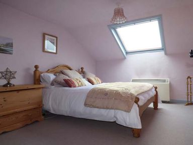 A bedroom with a wooden bed and chest of drawers under a skylight window at High House in Newton in Cartmel near Cartmel