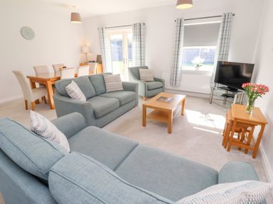 A living room with a sofa, dining table and television at The Haven in Embleton