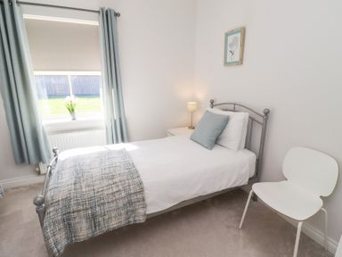 A bedroom with a bed, lamp, and chair at The Haven in Embleton