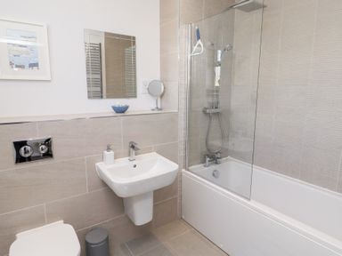 A bathroom with a shower and tub, sink, mirror, and toilet at The Haven in Embleton
