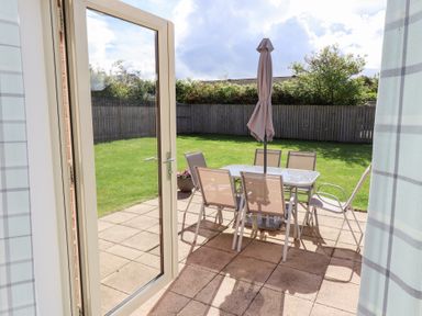 A patio with table and chairs under an umbrella at The Haven in Embleton