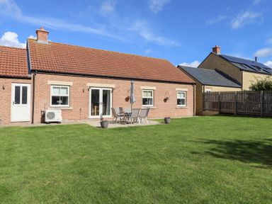 A garden with a brick house and patio furniture at The Haven in Embleton