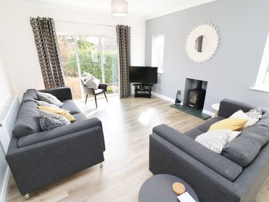 A living room with two grey sofas a chair television and a fireplace at Wysteria Cottage in Windermere