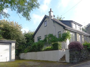 Exterior of a two story house with white walls a chimney stairs and a garage at Wysteria Cottage in Windermere