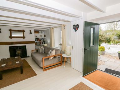 A living room with a sofa and fireplace at Fern Cottage in Aberporth