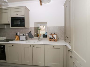 A kitchen with cabinets and appliances at Fern Cottage in Aberporth
