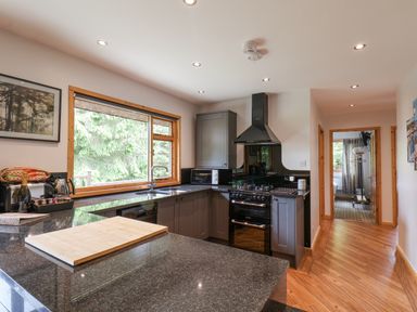 A kitchen with dark countertops cabinets a stove microwave and a window with trees outside at Pond Farm Woodlands in Ugthorpe