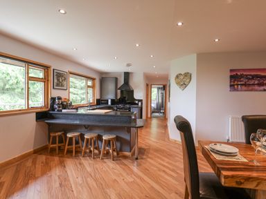 A kitchen and dining area with wooden stools at a counter and a wooden dining table at Pond Farm Woodlands in Ugthorpe