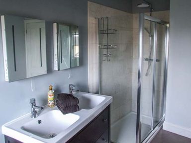 A bathroom with a double sink vanity and a glass-enclosed shower at Woodland Cottage in Malvern