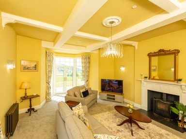 A living room with sofas coffee table fireplace and television at Old Rectory House Caersws