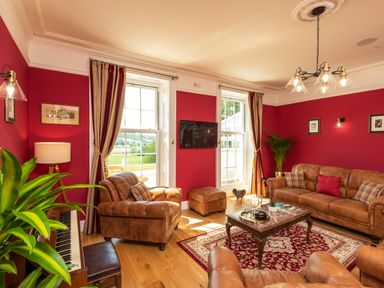 A living room with leather sofas a coffee table and a piano at Old Rectory House Caersws