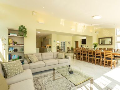 A living room with beige sofas a glass coffee table and a wooden dining table with chairs at Old Rectory House Caersws