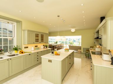 A kitchen with center island with breakfast items and cabinets along walls at Old Rectory House in Caersws