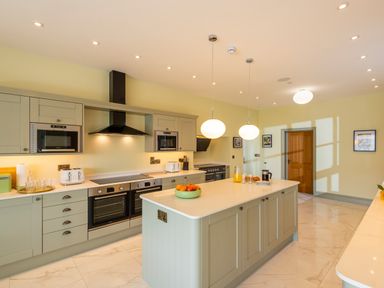 A kitchen with an island countertop ovens toasters and hanging lights at Old Rectory House in Caersws