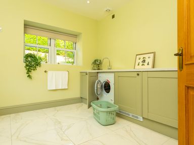 A laundry room with a washing machine cabinet a window with a towel and greenery at Old Rectory House in Caersws