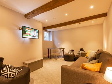 A living room with a wall mounted TV couch bean bags and a desk at Old Rectory House in Caersws