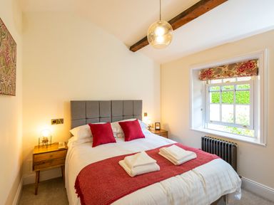 A bedroom with a bed with red pillows and throw at Old Rectory House in Caersws