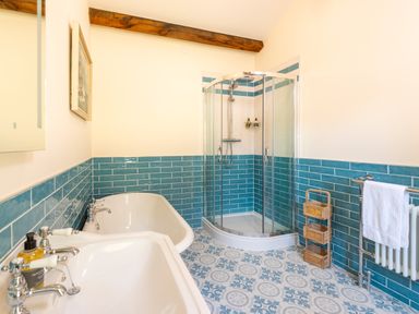 A bathroom with a sink bathtub and shower enclosure with blue tiles on the walls and patterned floor tiles at Old Rectory House in Caersws