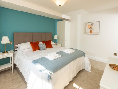 A bedroom with a bed with pillows and folded towels a wardrobe two bedside tables and lamps at Old Rectory House in Caersws