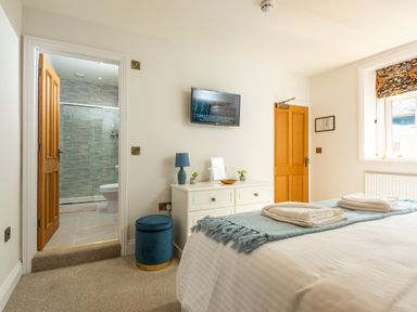 A bedroom with a bed towels a dresser and a door leading to a bathroom at Old Rectory House in Caersws