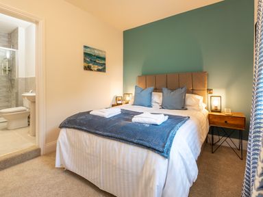 A bedroom with a bed two blue pillows and bedside tables at Old Rectory House in Caersws