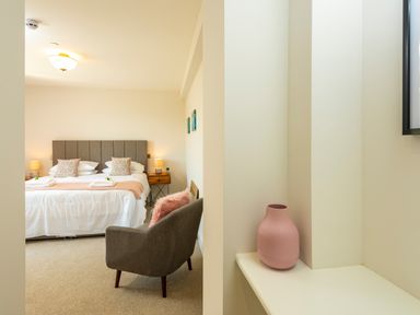 A bedroom with a double bed bedside tables armchair and a pink vase on a shelf at Old Rectory House in Caersws