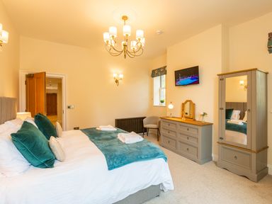 A bedroom with a bed dresser wardrobe chair and television at Old Rectory House Caersws