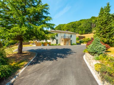 A house with a driveway surrounded by trees and greenery at Old Rectory House in Caersws