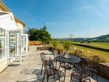 A patio with metal table and chairs overlooking fields at Old Rectory House in Caersws