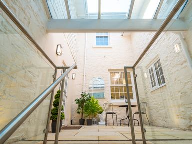 An enclosed courtyard with glass roof plants metal chairs and table at Old Rectory House in Caersws