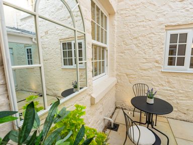 A small outdoor patio with a black metal table and chairs and a potted plant at Old Rectory House in Caersws