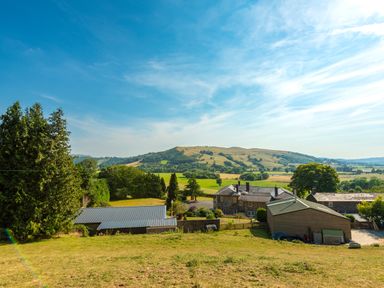 A countryside view with buildings trees and hills at Old Rectory House in Caersws