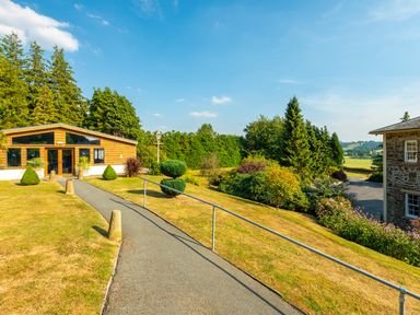 A paved pathway with railings leading to a wooden building surrounded by grass and trees at Old Rectory House in Caersws