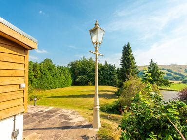 A garden with a vintage street lamp next to a wooden building at Old Rectory House in Caersws