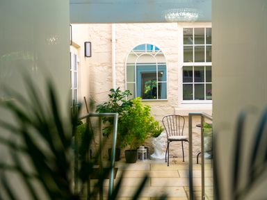 A small patio with potted plants a mirror a black metal chair and a statue head at Old Rectory House in Caersws