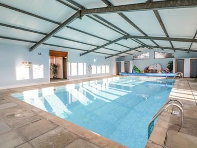 An indoor swimming pool with clear water and metal handrails at Old Rectory House in Caersws