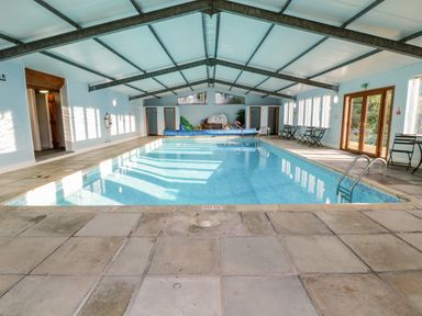 An indoor swimming pool with chairs tables and pool toys at Old Rectory House in Caersws