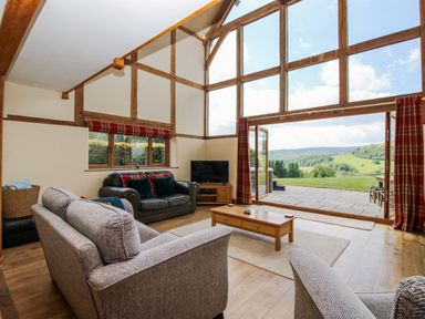 A living room with large windows and furniture at The Hayloft in Bleddfa near Knighton