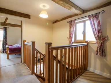 A landing with wooden stairs and a window at The Hayloft in Bleddfa near Knighton