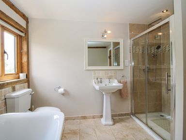 A bathroom with a bathtub, toilet, sink, and shower at The Hayloft in Bleddfa near Knighton