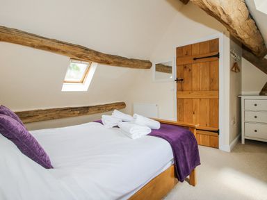 A bedroom with a bed and wooden beams at The Hayloft in Bleddfa near Knighton