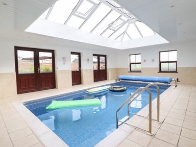 An indoor swimming pool with floatation devices and a glass ceiling at Ty Newydd in Llangadfan