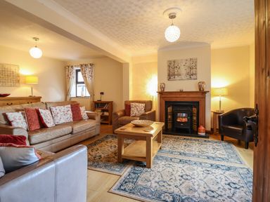 A living room with sofas armchairs a wooden coffee table fireplace and lamps at Ty Newydd in Llangadfan