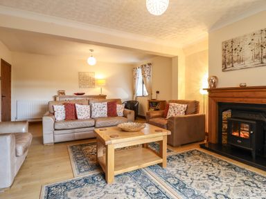 A living room with leather sofas wooden coffee table patterned rugs and a fireplace at Ty Newydd in Llangadfan