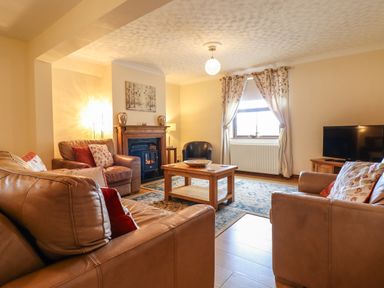 A living room with leather sofas a wooden coffee table a fireplace and a television at Ty Newydd in Llangadfan